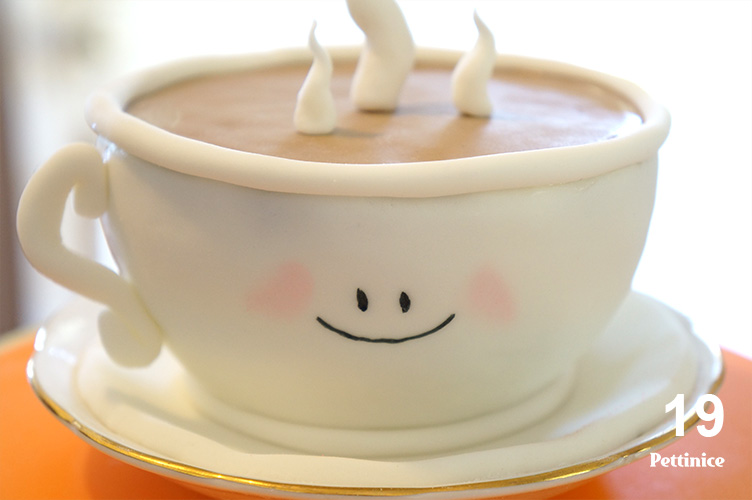 19. Use edible glue to adhere the tea cup handle. (Royal Icing or melted chocolate can also be used for this step). Use edible marker to draw a smiley face on the tea cup, draw the two eyes and the mouth. Pink petal dust can be lightly brushed on to give the effect of rosy cheeks.