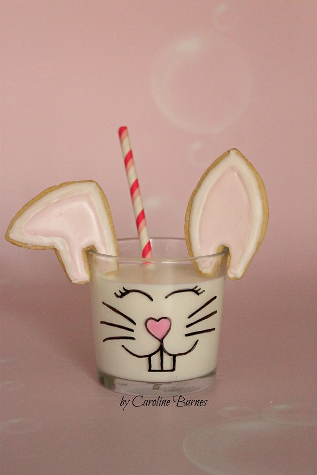 Bunny ear cookies suspended over a glass of milk  by Caroline Barnes