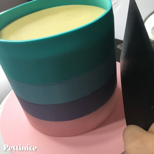 For the last colour at the top of the cake, cut it bigger, so if you were cutting 1.5" stripes, make it 2" tall instead so that it sits above your cake and you can then get a straight & even cut using your razor blade.