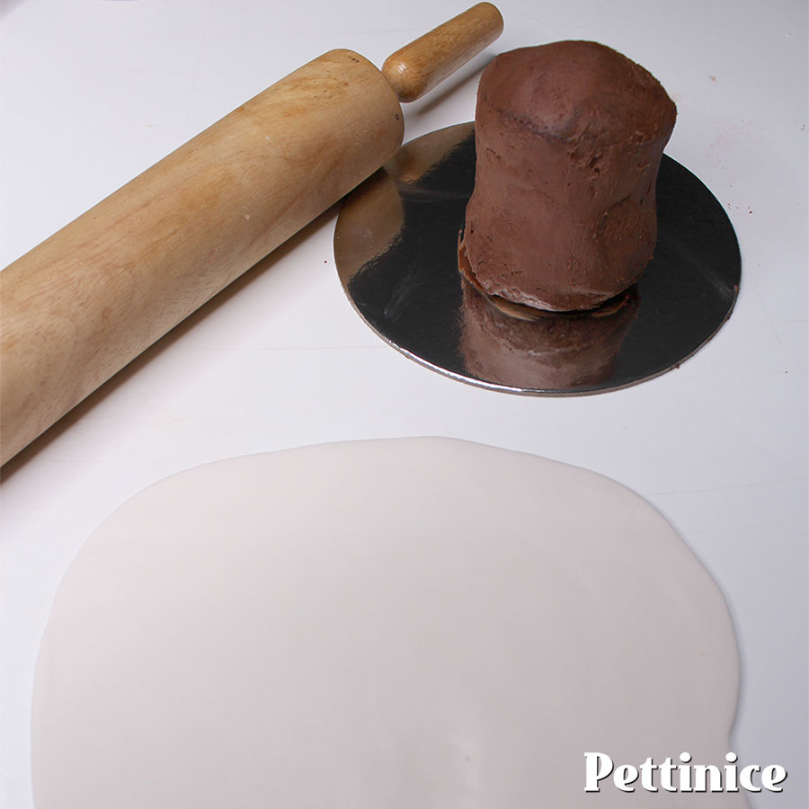 If your icing has hardened, brush or spray lightly with water, fat, or diluted jam.  Roll out your Pettinice fondant.