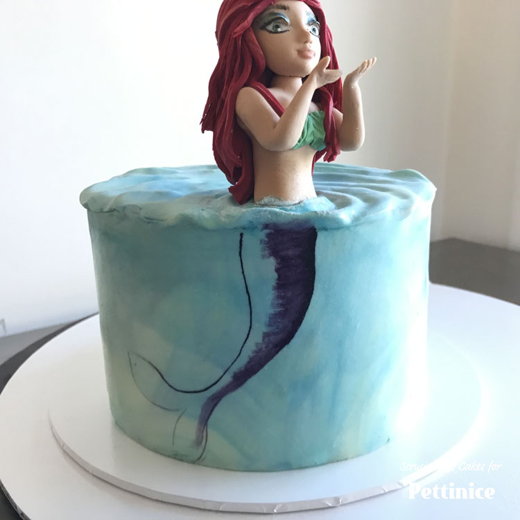 Paint an outline and make sure it lines up with where the figurine enters the ‘water’. The left hand side of the mermaid is closer to the edge of the cake so I am going to make the right hand side be darker.