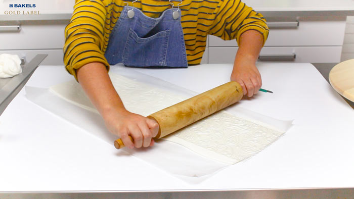 Transfer your fondant on top of a sheet of baking paper.  This will makes it easier to move around and cut, and wrap around your cake later.  This part is optional, but you can emboss textures for your toilet paper.