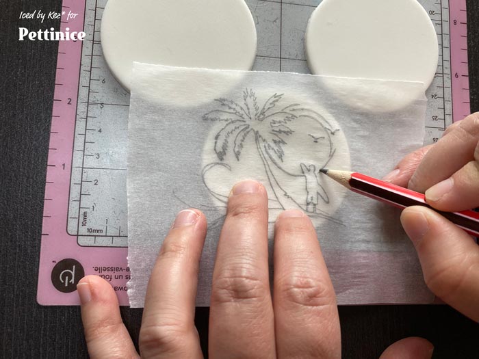 Step 5. Now take the baking paper with the traced image, bring it over to your fondant circle, line it up, the pencil side on the fondant.  Using your sharpened pencil trace over the image again, transferring it onto the fondant.  Do this for each design.