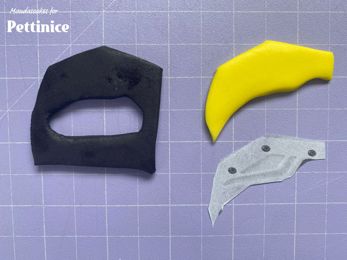 Cut out the handle of the saw template, roll a piece of black fondant and use the template to cut out a handle.  I’ve also cut an extra piece of yellow detailing from the template.