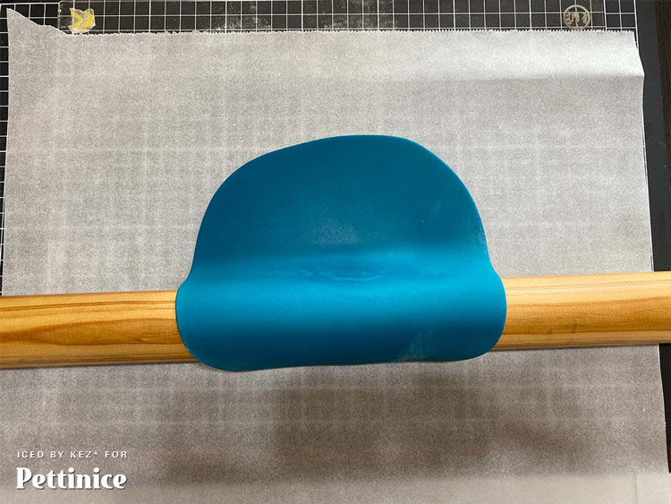 Using your rolling pin lift the fondant up and take it over to your Acrylic Set up Board (or Cake drum) that has been covered in baking paper.  Lay the fondant in the center of the baking paper with the good side down (the side with the cornflour on it will be facing up).