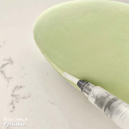 Use a damp brush to smooth away any excess royal icing or glue. Put the egg to one side to dry.