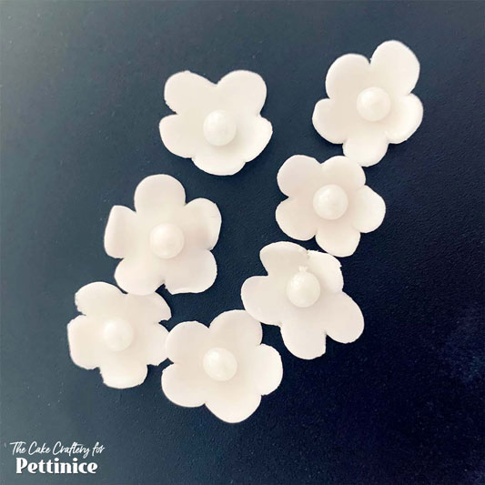 Pinch each petal between your thumb and forefinger to thin and curl upward, or use a ball tool. Glue a sugar pearl into each centre.
