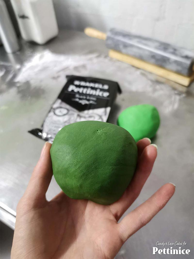 Add a small bit of black Pettinice to about half of your left-over piece of green that you trimmed from your cake to get a nice deep green for the melon stripes.